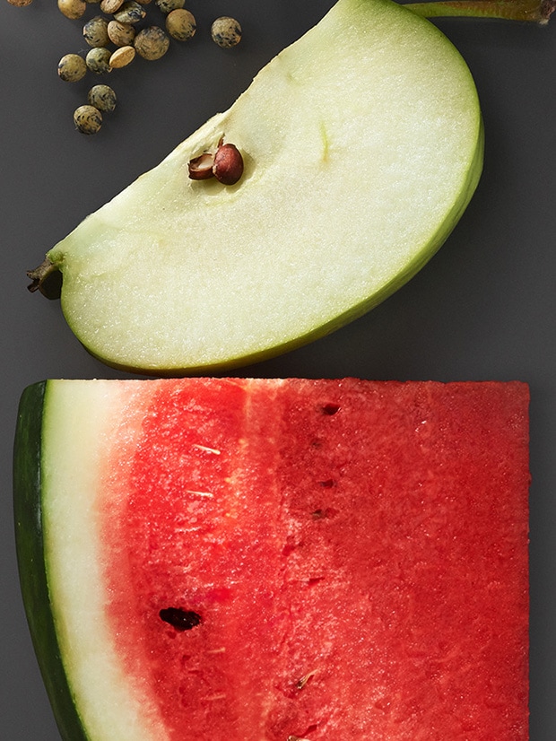 Gros plan d'une pomme et d'une tranche de pastèque sur fond gris foncé